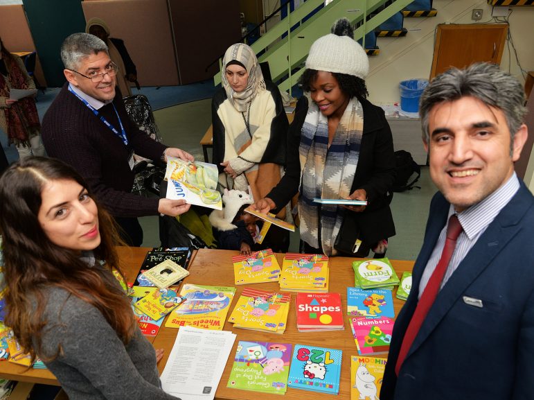 Nada Hassanatou project officer from the National Literacy Trust, Sabir Zazai director of CRMC and Abdul Munen Radwan community participation officer for CRMC hand out childrens books to Carine and her friend who are refugees from the Democratic Republic Of Congo. 46.016.009.cov.jm1
